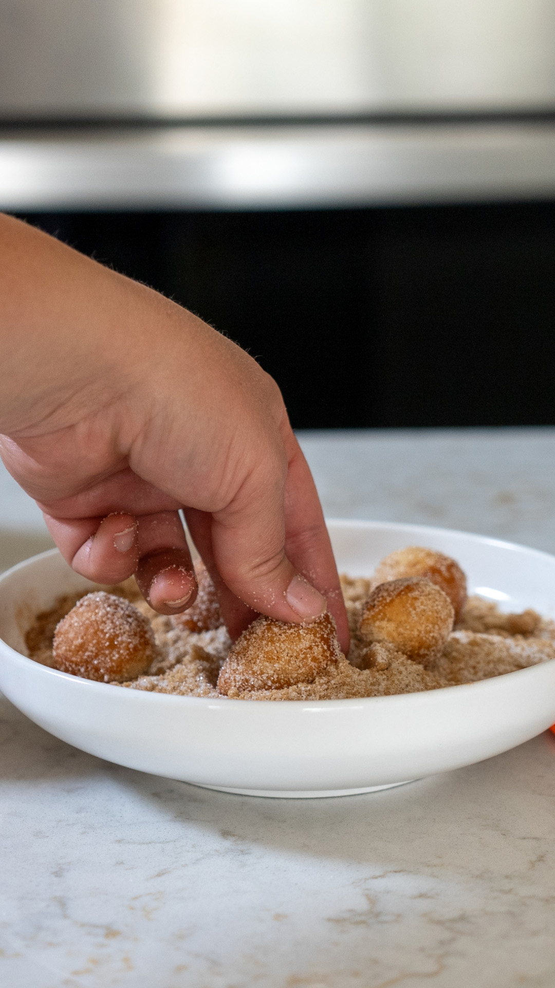 Donut holes being coated with sugar mixture.