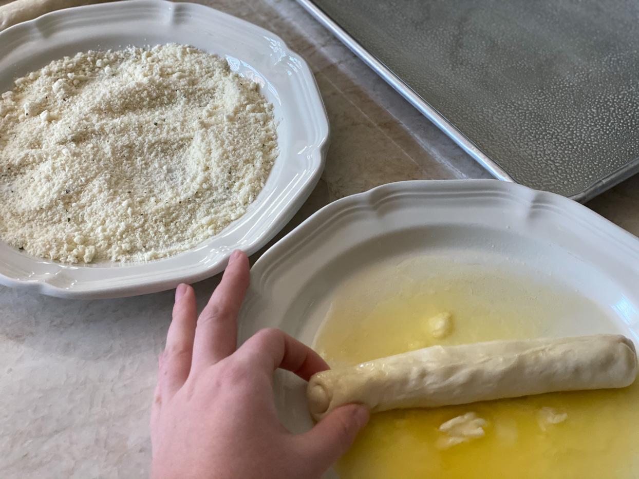 Recipe being rolled in melted butter.