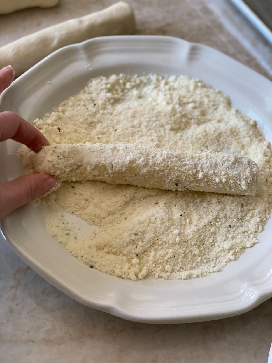 Recipe being rolled in grated cheese.