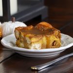 A piece of pumpkin bread pudding with brown sugar sauce over the top.