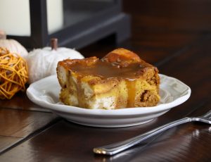 A piece of pumpkin bread pudding with brown sugar sauce over the top.