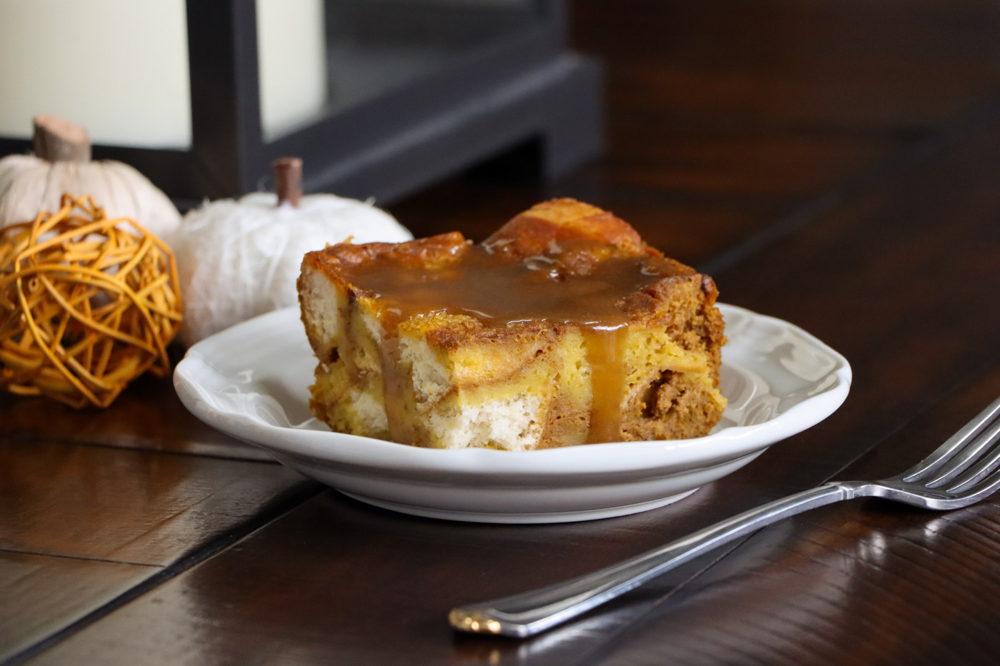 A piece of pumpkin bread pudding with brown sugar sauce over the top.