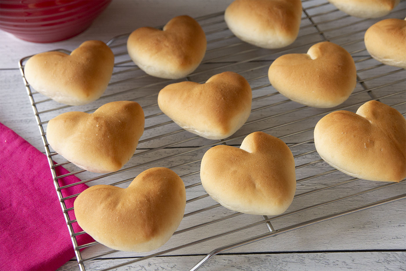 Valentine heart dinner rolls on a baking rack.