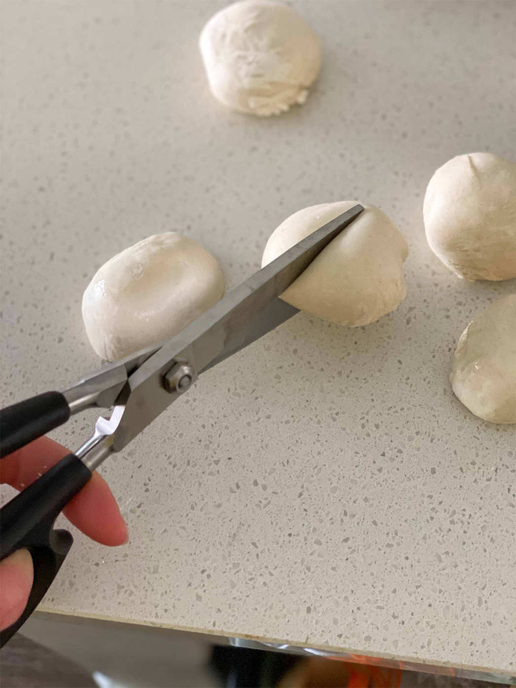 Dinner Roll dough being cut in half.