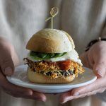 Eggplant parmesan slider being held on a plate.