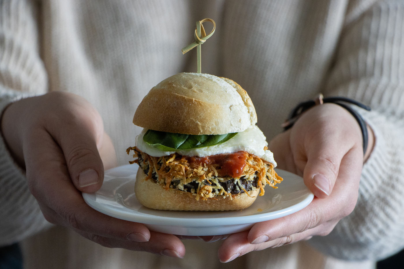 Eggplant parmesan slider being held on a plate.