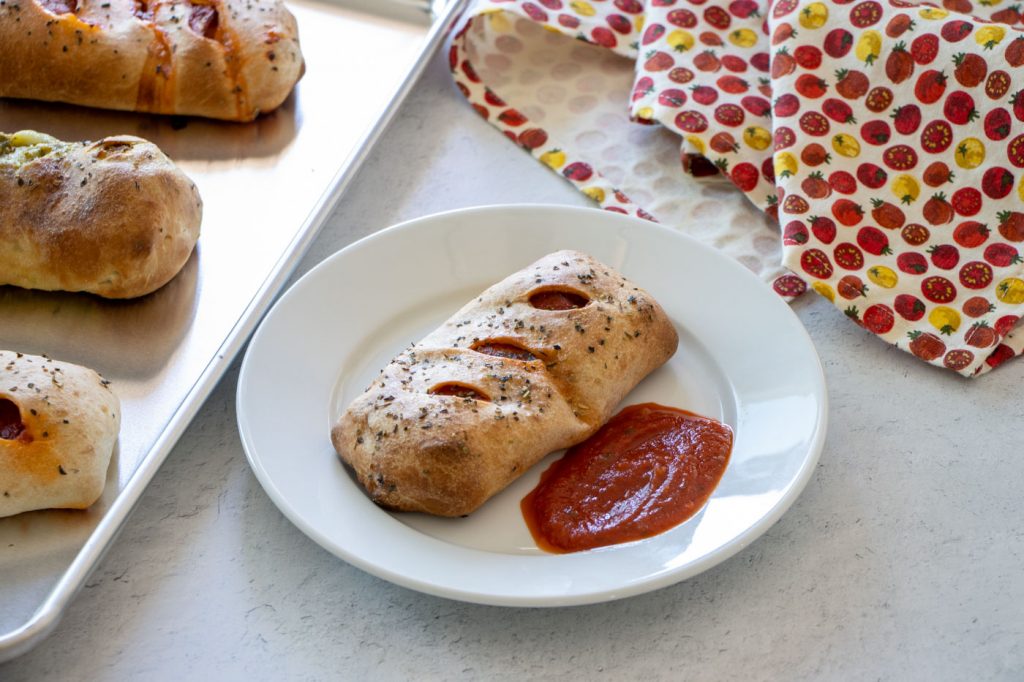 Pizza Pocket served on a plate with marinara sauce.