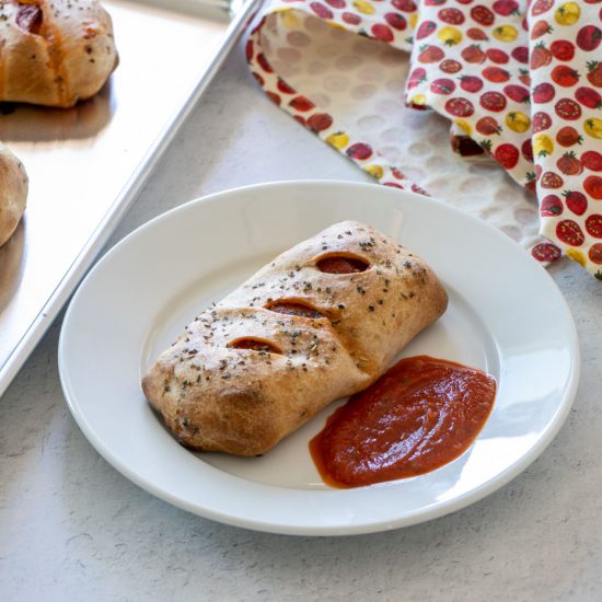 Pizza Pocket served on a plate with marinara sauce.