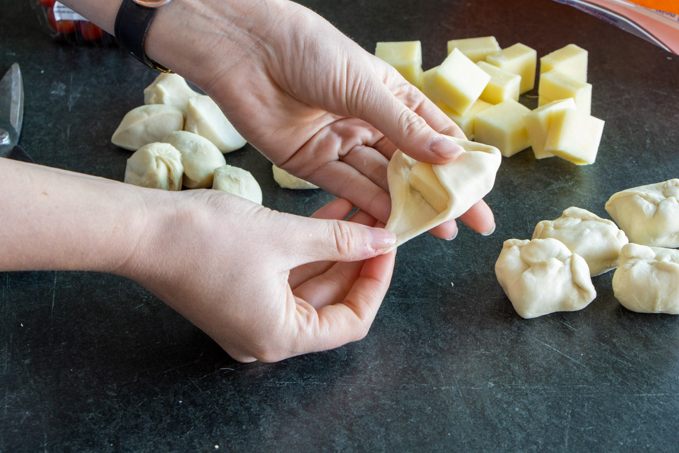 Wrapping roll dough around a cheese cube.