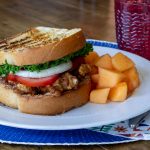 Fried chicken sandwich on a white plate and blue placemat.