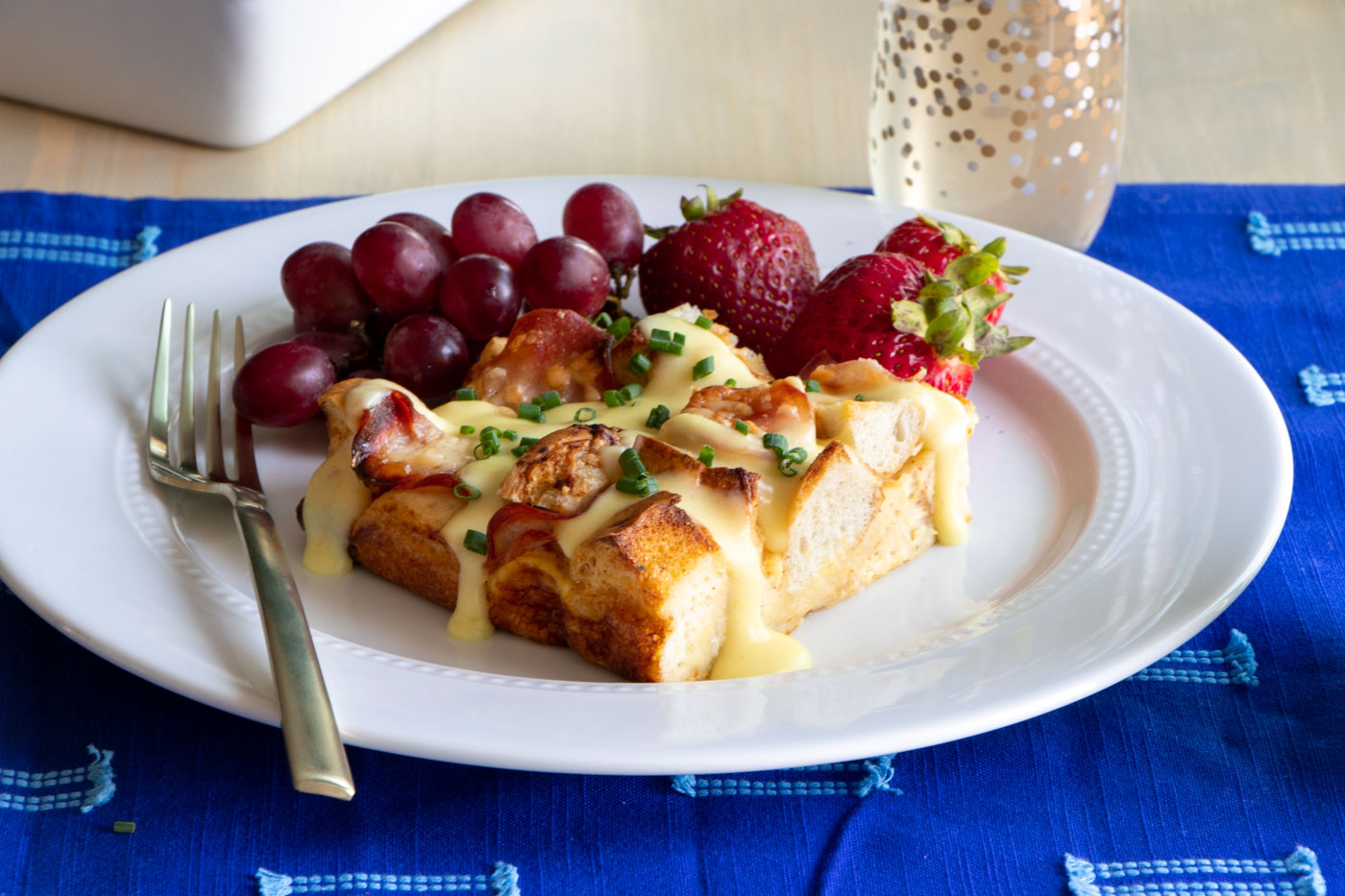 Eggs Benedict Breakfast Casserole on plate with fruit.