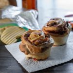 Pizza muffins served as a school lunch with chips and carrots; brown paper bag in the background.