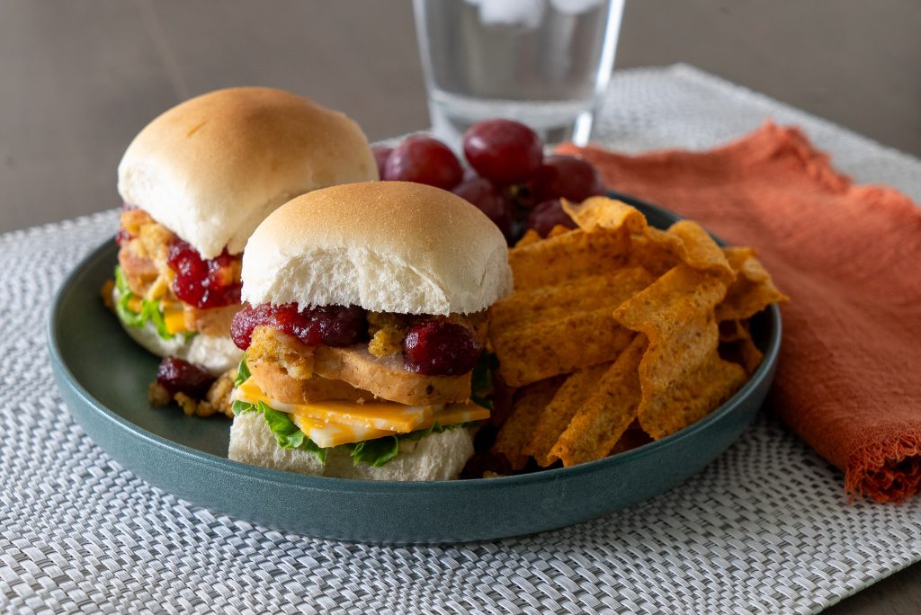 Leftover Sliders on a plate with chips and grapes.